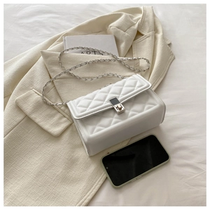 Detailed view of white quilted crossbody bag with metal chain strap and phone for scale