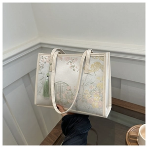 Détail du sac cabas beige orné de motifs floraux classiques et d'un gland déco