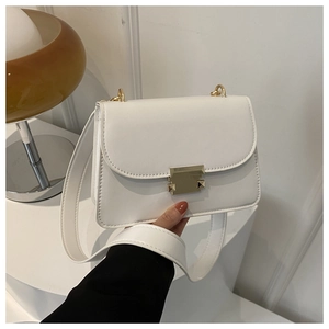Detail of white leather crossbody bag with golden metal buckle and wide strap