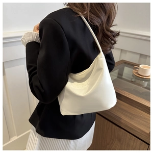 Close-up of white minimalist shoulder bag with dreams and upwards embroidery detail