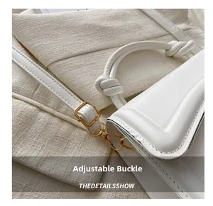 Detail view of white handbag featuring a knotted handle and adjustable golden metal buckle