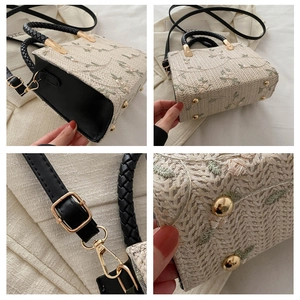 Detail of beige woven tote with floral embroidery, black handles and metal feet