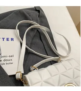 Detail view of white quilted PU leather crossbody bag with golden metal hardware