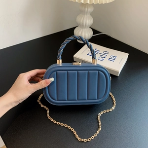 Elegante borsa a mano box blu navy con motivo trapuntato e catena dorata in una natura morta