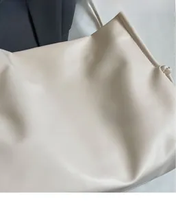 Dettaglio della borsa tote beige con consistenza in pelle morbida e nodo alla moda sulla tracolla