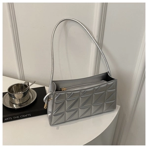 Detail of silver quilted crossbody bag featuring triangular stitching and gold zipper