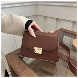 Close-up of brown vintage crossbody bag featuring gold metal buckle and wide strap