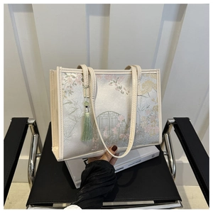 Détail d'un sac cabas floral avec motif cerisier et élégant pendentif à pampille verte
