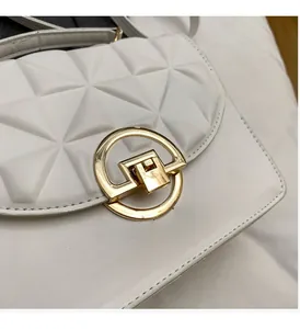 Detailed close-up of white geometric quilted leather handbag with gold round lock
