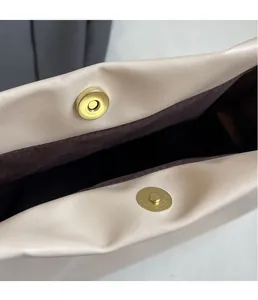 Dettaglio della fibbia magnetica dorata su una borsa a tracolla minimalista in pelle beige
