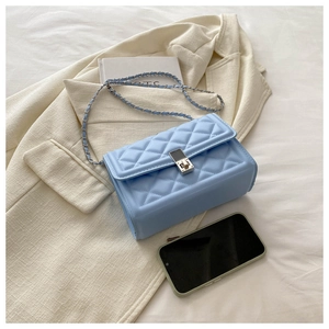 Detail view of light blue quilted crossbody bag with silver chain and metal turn lock
