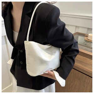 Close-up of white soft leather shoulder bag featuring minimalist embossed text detail