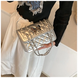 Détail du sac bandoulière argenté matelassé avec fermoir papillon et chaîne