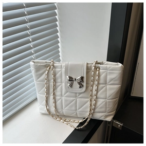 Detail of white quilted shoulder bag with silver bow clasp and metal chain strap