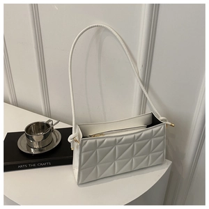 Detail of white geometric quilted texture and gold zipper on a chic faux leather bag