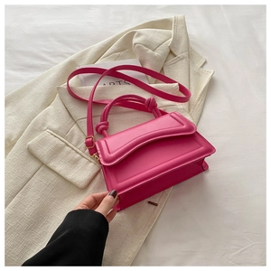 Detailed macro view of pink leather handbag with unique knotted handle on tweed fabric