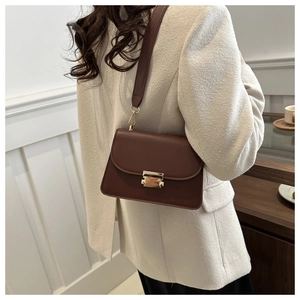 Detail view of a vintage dark brown leather shoulder bag with gold square metal buckle clasp