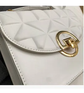 Detail of white PU leather bag with geometric quilting and golden metal round buckle