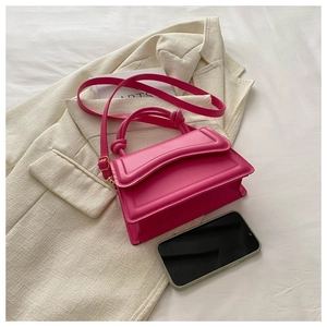 Mini magenta leather crossbody bag with knot handle detail and phone for size scale