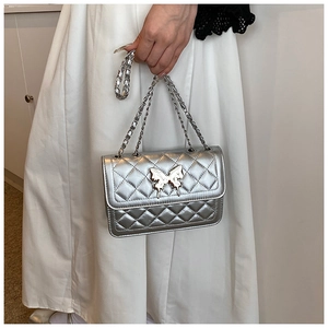 Détail du sac argenté matelassé avec fermoir papillon 3D et bandoulière en chaîne chic