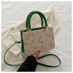 Detailed embroidery on woven handbag with green leather straps and gold metal hardware