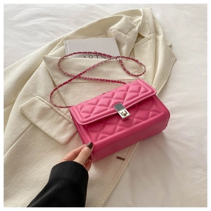 Detail of rose pink quilted crossbody bag with silver chain strap and square metal lock