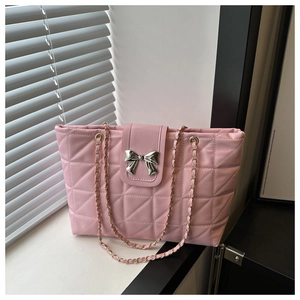 Close-up of pink quilted tote bag featuring a silver metal bow and woven chain strap