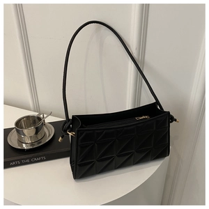 Detail of black quilted shoulder bag with geometric patterns and gold metal zippers