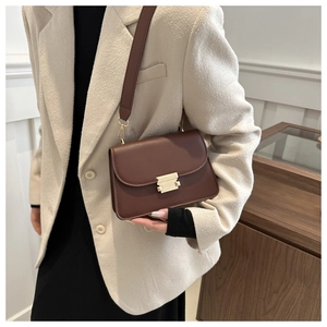 Close-up of a brown leather crossbody bag with metal clasp and wide shoulder strap