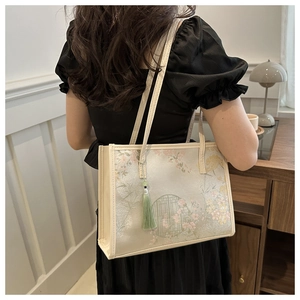 Détail d'un grand sac cabas brodé avec motifs floraux orientaux et pompon vert
