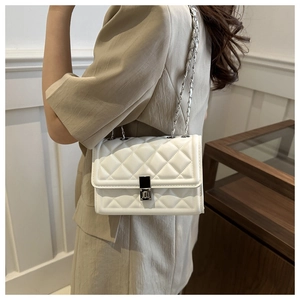Close-up of white quilted crossbody bag featuring silver chain strap and metal turn-lock