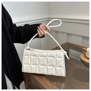 Detailed view of white quilted faux leather mini handbag with top handle and stitching