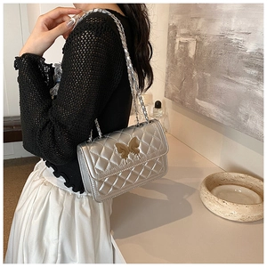 Détail du sac argenté matelassé avec fermoir papillon doré et bandoulière en chaîne