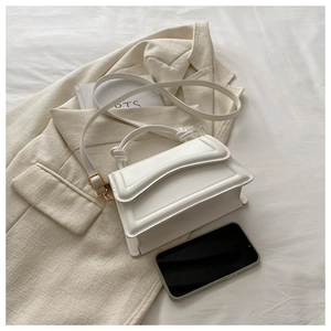 Detail of minimalist cream handbag with decorative knot handle on beige blazer background