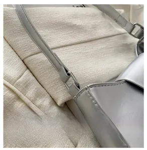 Detail of silver shoulder bag showing metal buckle connection and fine edge stitching