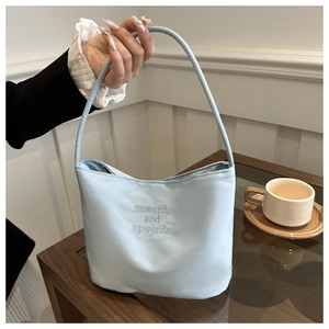 Close-up of light blue nylon bag with onwards and upwards embroidery on a cafe table