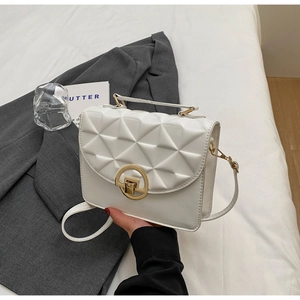 Close-up of white crossbody bag featuring geometric triangle quilting and gold clasp