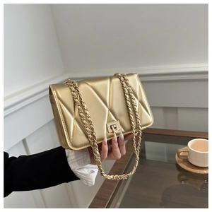 Detailed view of gold quilted chain bag with V-shaped stitching and square metal turn lock