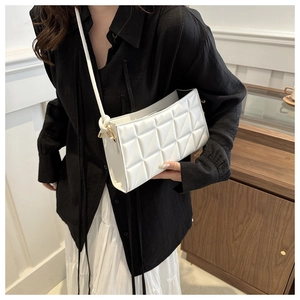 Detailed view of a white quilted crossbody bag with stylish triangle stitching texture