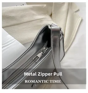 Detail of silver metallic underarm bag showing smooth surface and metal zipper hardware