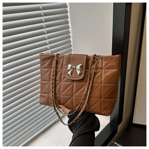 Detail of brown quilted tote bag featuring silver bow buckle and gold chain strap