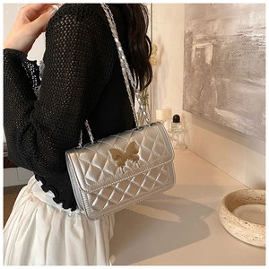Détail du sac bandoulière argenté matelassé avec fermoir papillon en métal doré
