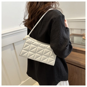 Detail of white leather crossbody bag featuring geometric triangle quilting and slim strap