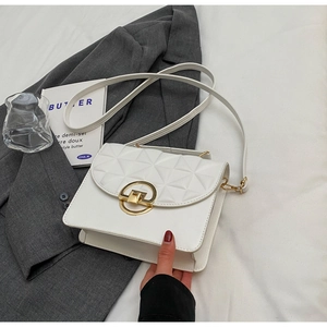 Detailed view of white crossbody bag featuring geometric quilting and golden round clasp