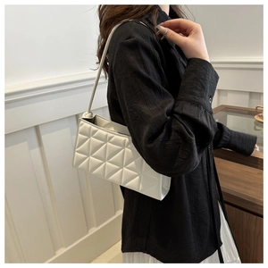 Detail of white quilted crossbody bag featuring triangular stitching on a model