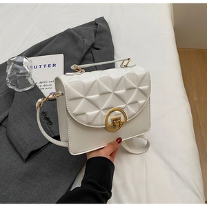 Detailed shot of white crossbody bag with geometric quilted pattern and gold ring clasp