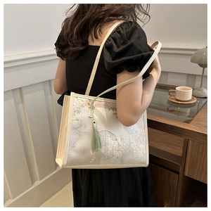 Détail d'un sac cabas floral avec pendentif à glands dans un cadre intérieur chaleureux