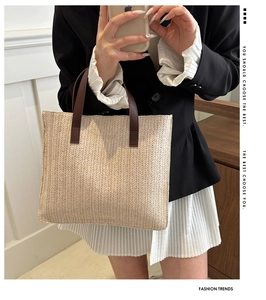 Detail of the woven herringbone texture and premium brown leather straps on the straw tote bag