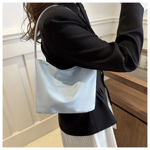 Close-up of light blue satin bucket bag featuring elegant onwards and upwards embroidery