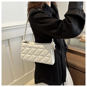 Detail of white quilted crossbody bag with stylish knot strap and gold metal hardware